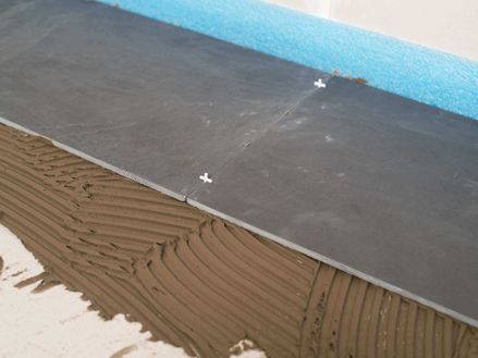 Voegen met kruizen als afstandhouders tussen twee leistenen tegels