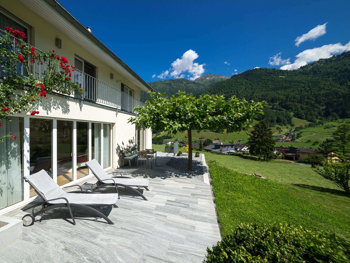 Terras met granieten platen, ligstoelen en bergen op de achtergrond