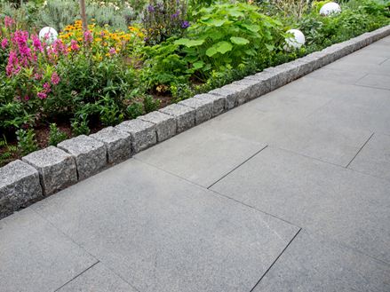 Pad met granieten plaat Padang Dark en aangrenzend bloembed