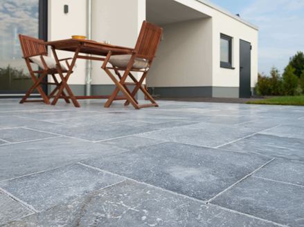 Kikkeruitzicht op terras met marmeren platen en houten meubilair