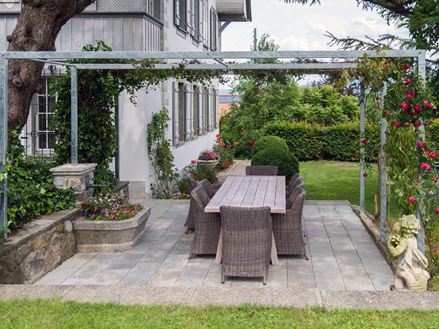 Kandla Grijze zandstenen plaat op een terras met pergola en aangrenzend gazon