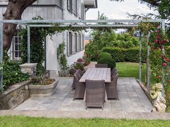 Kandla Grijze zandstenen plaat op een terras met pergola en aangrenzend gazon