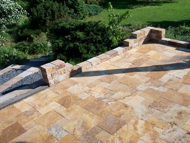 Gouden travertinplaat gelegd in een gemengde verbinding met natuurstenen muur en aangrenzende tuin