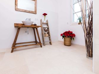 Badkamer met houten meubilair en lichtgekleurde tegels van natuurlijk kalksteen als vloerbedekking