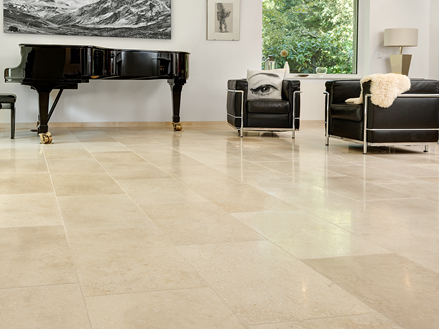 Lichte woonkamer met beige kalkstenen vloeren, moderne bank en een vleugelpiano