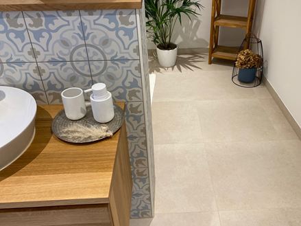 Badkamer met houten elementen en decoratieve plant, tegels in kalksteenlook uit Sevilla als vloerbedekking