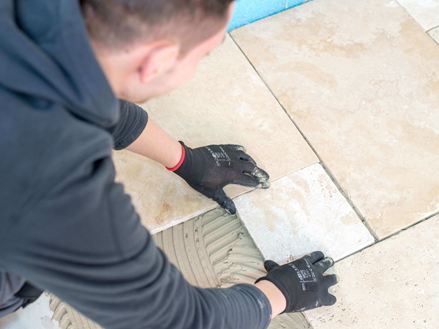 Man legt travertin tegels in licht beige in een gemengd patroon