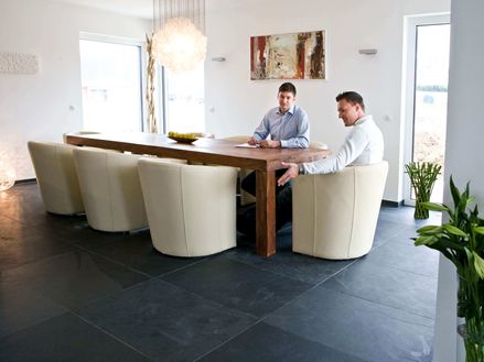 Eettafel met witte fauteuils en twee personen op Mustang leistenen tegel in donkergrijs