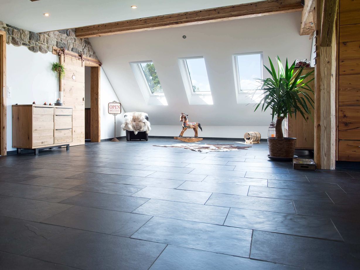 Kamer met antracietkleurige leistenen vloer en houten meubels, witte muren