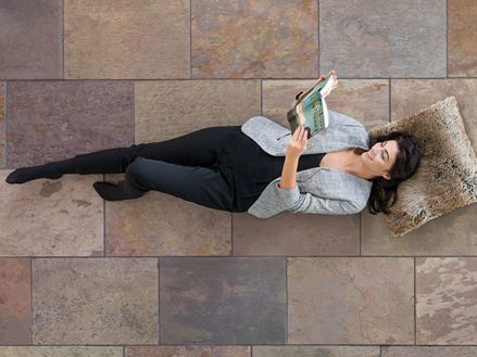 Vrouw liggend op gekleurde leistenen tegels Peacock Multi Color en lezend