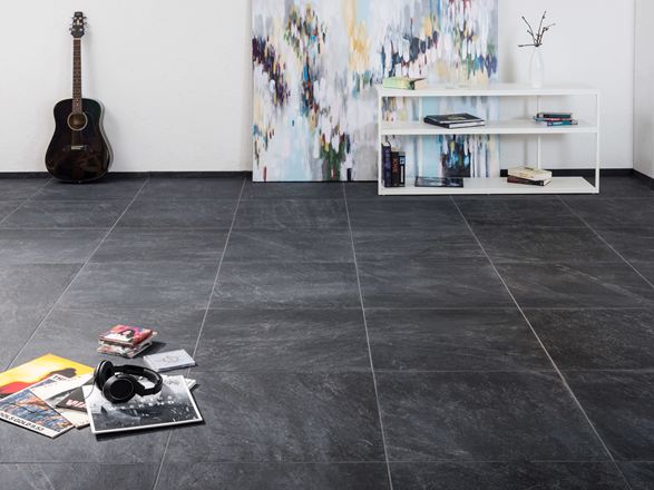 Moderne keramische tegels met leisteenlook in een woonkamer met een modern schilderij op de achtergrond en een gitaar aan de muur