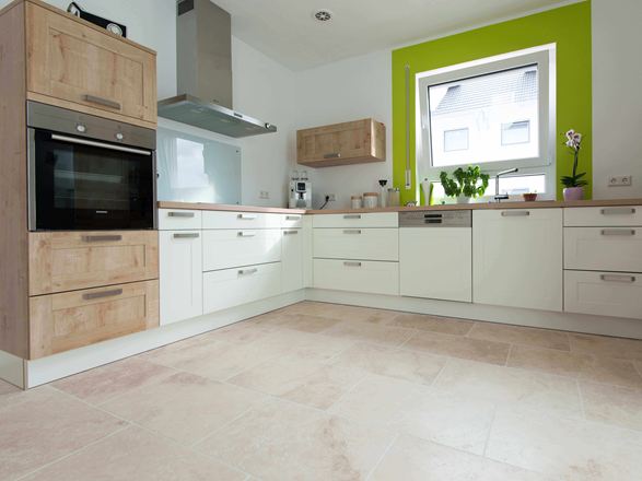 Keuken in wit met houten elementen en groen raamkozijn op Lichte travertin tegel met getrommeld, niet geëgaliseerd oppervlak