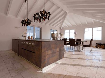 Kookeiland met wijnfleshouder aan het plafond, op de achtergrond eettafel en stoelen op gelegd Travertin Light met getrommeld, niet geÃ«galiseerd oppervlak