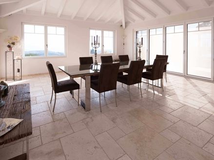 Eetkamer met hoog plafond, tafel en stoelen op Travertin Licht in Romeins verband
