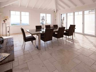 Eetkamer met hoog plafond, tafel en stoelen op Travertin Licht in Romeins verband