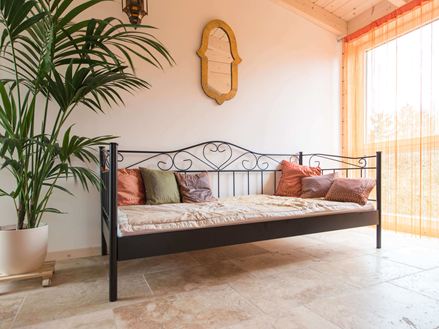 Slaapkamer met bed, plant en rustiek travertin op de vloer