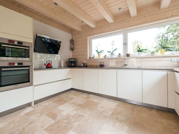 Keuken met witte meubels en beige rustieke travertin tegels als vloerbedekking
