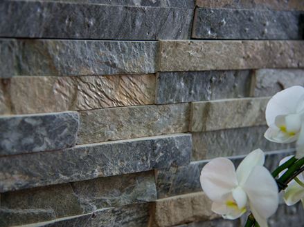 Witte orchideeÃ«n naast muur met kwartsiet Deoli Green gemaakt van losse slips