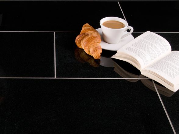 Donkere Nero Assoluto tegels met croissant, koffiekopje en een open boek