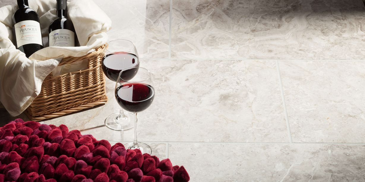 Twee wijnglazen staan naast een gevulde mand met aardbeien op gepolijste Silver Shadow marmeren tegels