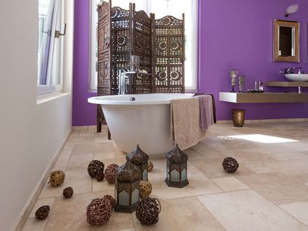 Travertin Lichte tegels in een badkamer met vrijstaand bad en paarse muur op de achtergrond