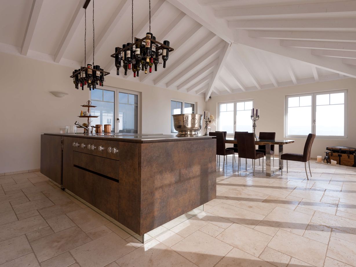 Kookeiland met wijnfleshouder aan het plafond, op de achtergrond eettafel en stoelen op gelegd Travertin Light met getrommeld, niet geÃ«galiseerd oppervlak