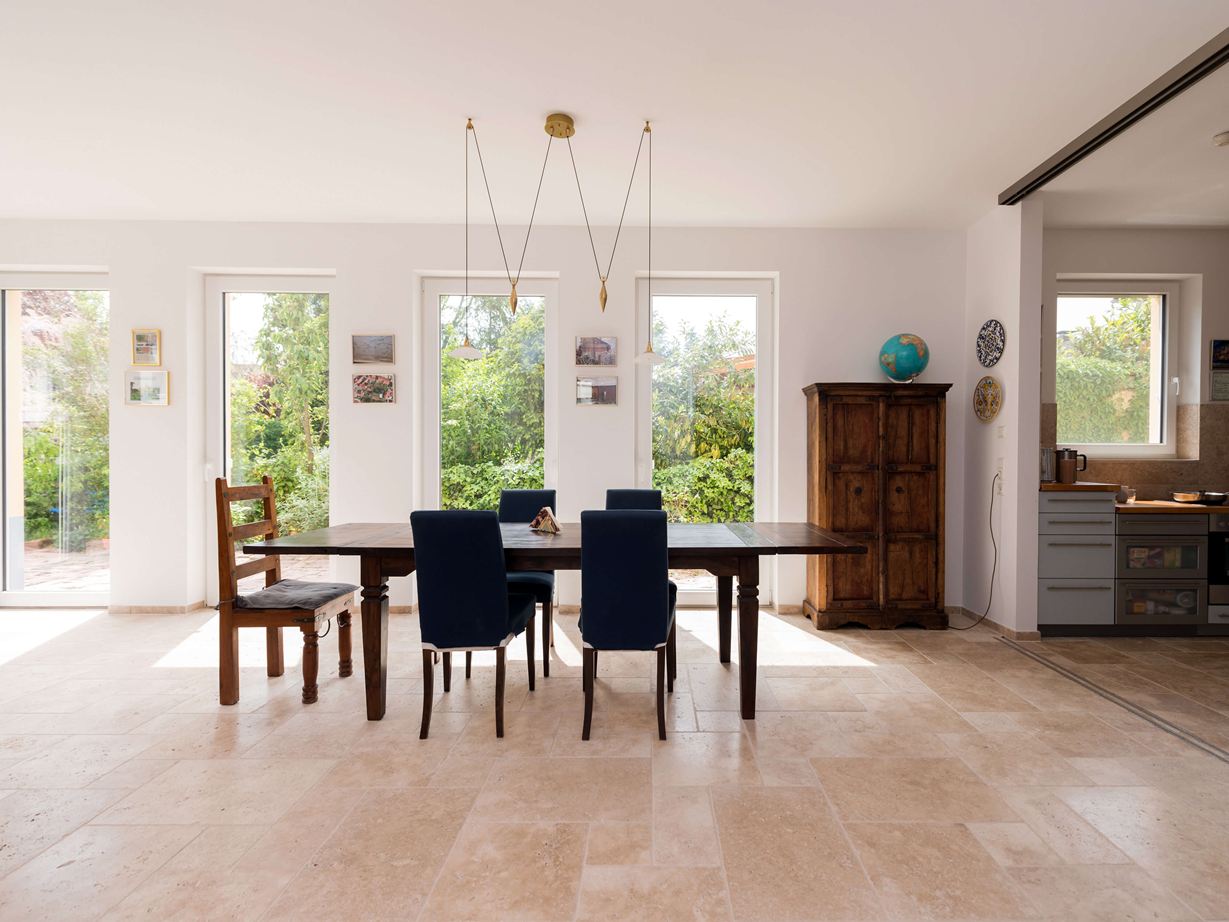 Lichte eethoek met houten meubels en beige travertin tegels als vloerbedekking