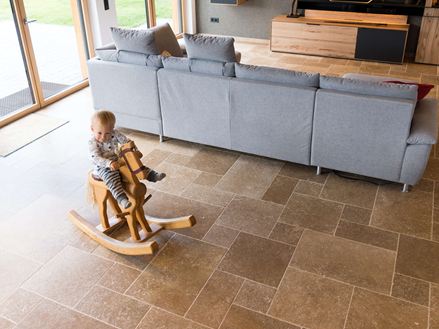 Kind zit op een hobbelpaard en speelt in de woonkamer met Noce SELECT travertinvloer