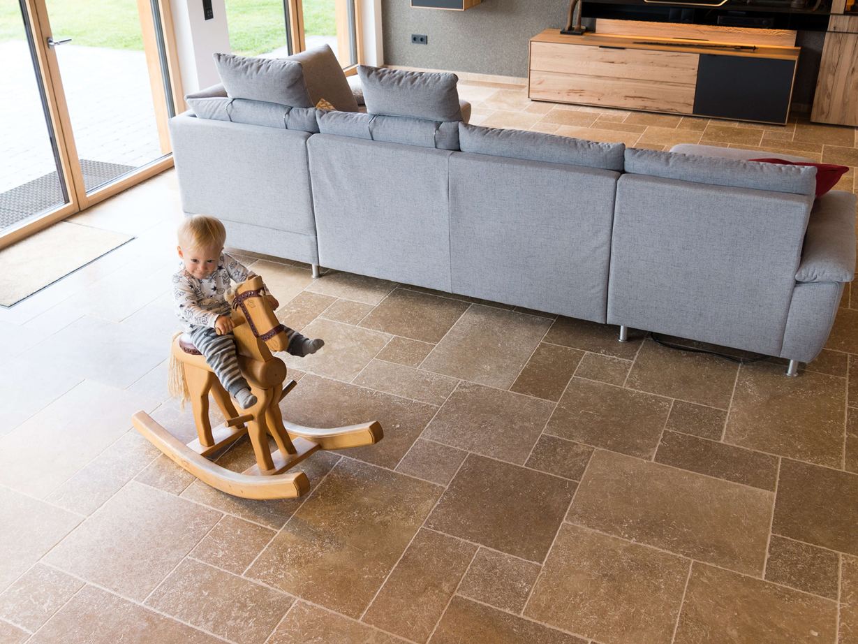 Kind zit op een hobbelpaard en speelt in de woonkamer met Noce SELECT travertinvloer