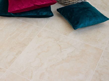 Kleurrijke kussens op fijne stenen tegels in een lichte travertin-look
