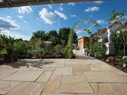 Natuurlijke tuin met lichtgekleurde zandsteenplaten Gele munt