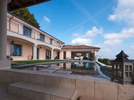 Zicht op het zwembad en het huis met lichte travertinplaat in een zachtbeige kleur