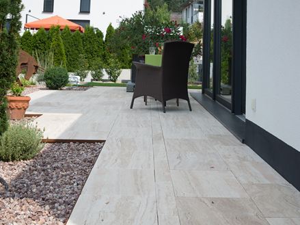 Modern terras met Natura travertin platen in houtlook en donkere rieten panelen