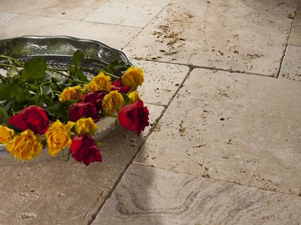 Een dienblad met rozen op gelegde travertin platen in beige en bruin