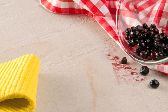 Gele doek, rode theedoek en een glazen schaal met bessen uitgetipt op natuursteen