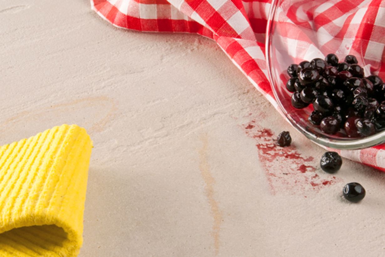 Gele doek, rode theedoek en een glazen schaal met bessen uitgetipt op natuursteen
