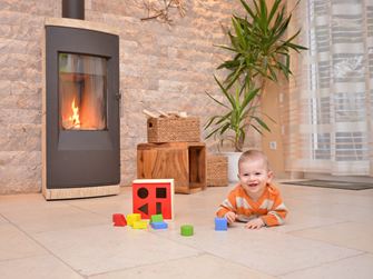 Baby speelt op een natuurstenen vloer voor een open haard