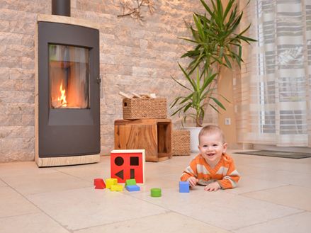 Baby speelt op een natuurstenen vloer voor een open haard