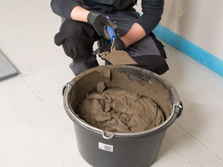 Tegelzetter voor een emmer natuursteenlijm