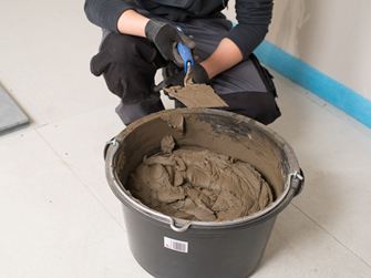 Tegelzetter voor een emmer natuursteenlijm