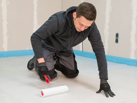 Tegelzetter brengt de primer aan met een roller