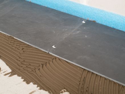 Voegen met kruizen als afstandhouders tussen twee leistenen tegels