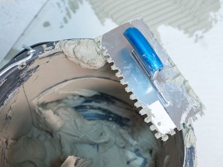 Een emmer natuursteenlijm en een getande spaan