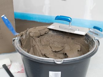 Een emmer natuursteenlijm en een getande spaan