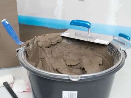 Een emmer natuursteenlijm en een getande spaan