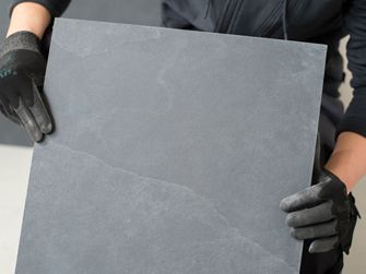 Tegelzetter houdt een leistenen tegel voor de camera