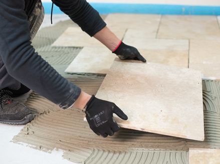 Travertin tegels worden in het lijmbed gelegd