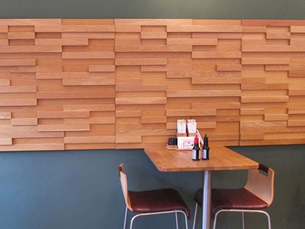 Een tafel met twee stoelen voor een grijze muur met bruine houten lambrisering in een bistro