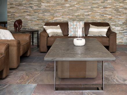 Woonkamer met bruine banken, rustieke kwartsiettegels als vloer en natuurstenen bekleding op de muur