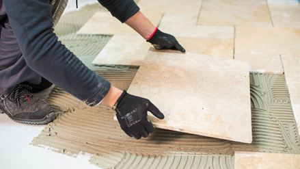 Een tegelzetter legt een travertin tegel